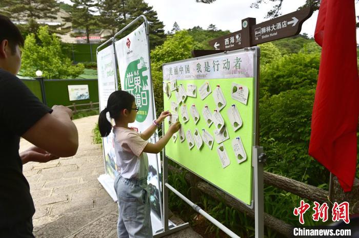 小朋友在环保墙上贴上自己写的环保宣传语 蔡季安 摄