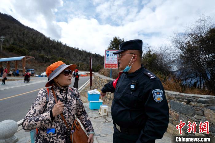 图为警务室民警为游客讲解景区内的相关注意事项。 江才云旦 摄