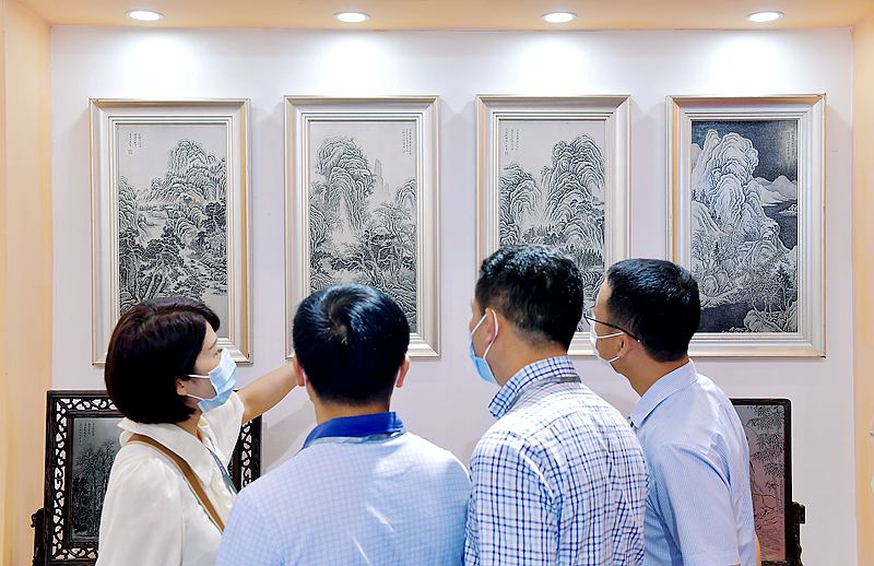 参展商正在向嘉宾介绍阜阳杜氏铜刻画作品。.jpg