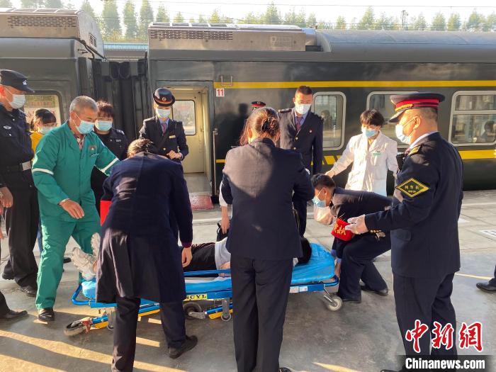 列车工作人员和120救护人员合力送产妇上救护车。　 张黎明 摄